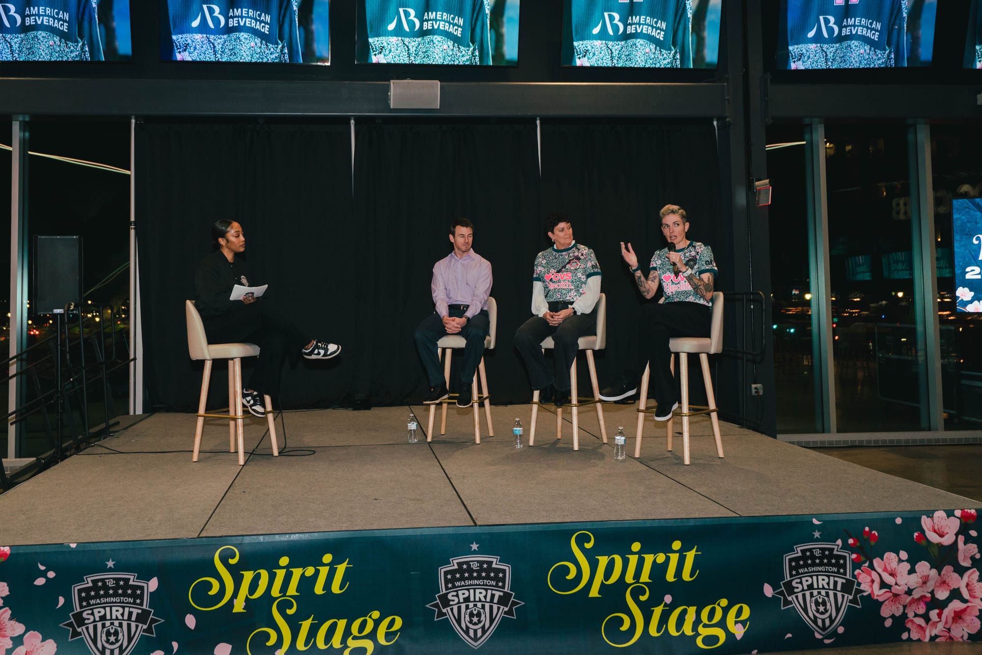 A photo from the Washington Spirit's kit reveal, with GM Nathan Minion, CEO Kim Stone, and CSO Haley Carter speaking on stage.