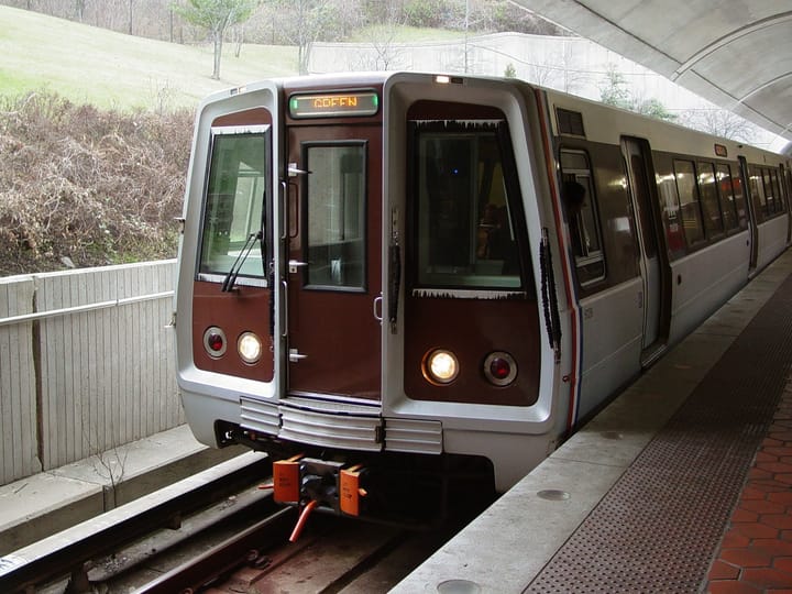 A photo of the front of a Metro train on the green line pulling into a station.